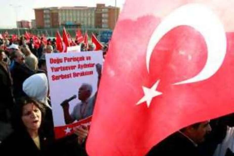 A supporter carries a sign with a portrait of Workers Party leader Dogu Perincek, one of the 86 defendants, as others wave Turkish flags outside the heavily guarded Silivri prison, 70 km (43 miles) west of Istanbul, October 20, 2008. A shadowy right-wing group went on trial in Turkey on Monday on charges of trying to topple Prime Minister Tayyip Erdogan's government. Eighty-six people, including retired army officers, politicians, lawyers and journalists, are accused of planning assassinations and bombings to sow chaos and force the military to step in. The sign reads: "Perincek and patriotic intellectuals should be released." REUTERS/Fatih Saribas  (TURKEY) *** Local Caption ***  FSA04_TURKEY-COUP-T_1020_11.JPG
