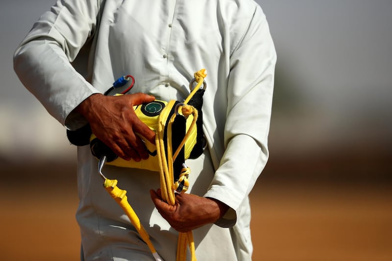 A handler holds a robotic jockey during Al Marmoom Heritage Festival.