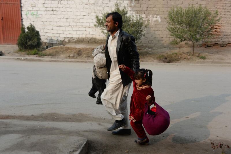 A man runs with two children near the Save the Children office. Noorullah Shirzada / AFP Photo