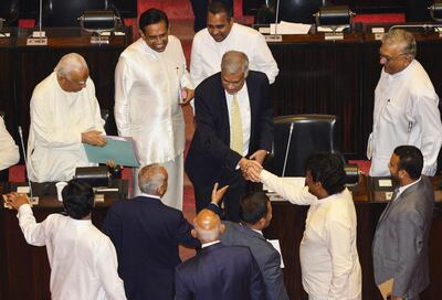 Sri Lanka's members of parliament shake hands with ousted prime minister Ranil Wickremesinghe (C) during a parliament session in Colombo on December 12, 2018. Sri Lanka's legislature voted overwhelmingly on December 12 to demand the reinstatement of prime minister Ranil Wickremesinghe, as a bitter power struggle headed for a government shut down within weeks. / AFP / LAKRUWAN WANNIARACHCHI
