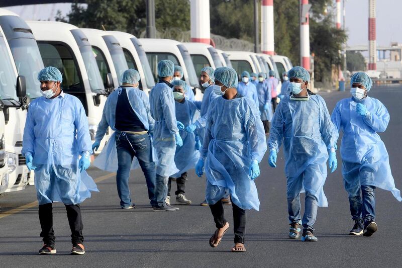 Health ministry workers, wearing protective outfits, wait on the tarmac of the Kuwait international Airportat to receive Kuwaitis returning from Frankfurt on March 26, 2020, to be taken to a hospital for novel coronavirus checkups, in the capital Kuwait City.  / AFP / STR
