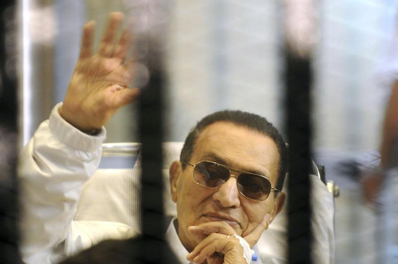 Former Egyptian president Hosni Mubarak waves to his supporters from behind bars as he attends a hearing in his retrial on appeal in Cairo, in 2013. AP Photo