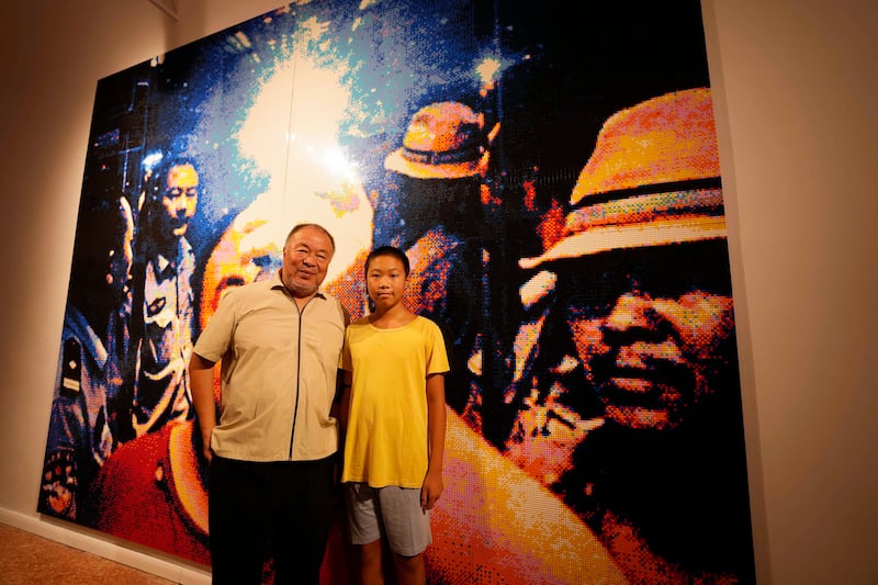 Chinese artist Ai Weiwei poses with his son Lao, 13, in front of a self-portrait made of Lego.