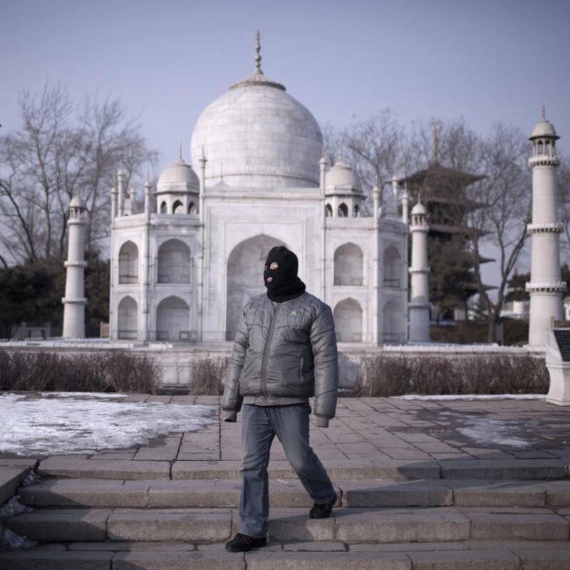 A man walking past a mini replica of the Taj Mahal.