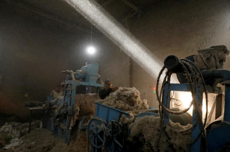 A labourer uses a piece of cloth as a mask to avoid dust while working at a cotton gin workshop in Peshawar, Pakistan.  Reuters
