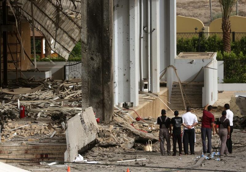 Civilians and security forces inspect the aftermath of a car-bomb attack. Hadi Mizban / AP Photo