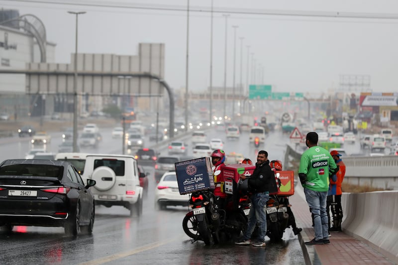 Drenched delivery drivers in Umm Suqeim, Dubai. Chris Whiteoak / The National