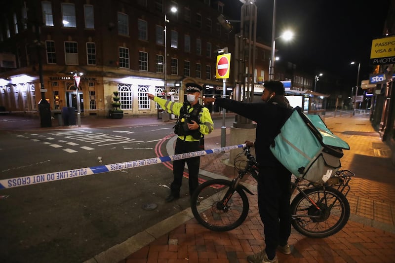 A police officer gestures next to a delivery rider at the scene of reported multiple stabbings in Reading. REUTERS