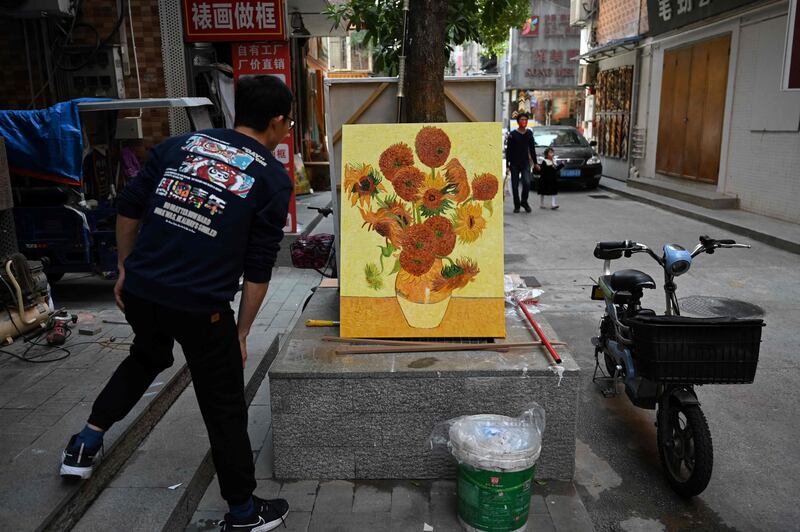 A vendor checks a replica of Vincent van Gogh's Sunflowers in an alley in Dafen 