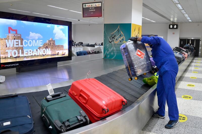 A worker carries luggage at Rafik Hariri international airport during its re-opening in Beirut at 10 per cent capacity, which is expected to bring in around 2,000 travellers per day.  EPA