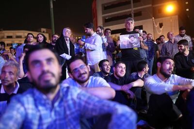 People watch the debate of presidential candidates at a park in Tehran, Iran. WANA via Reuters