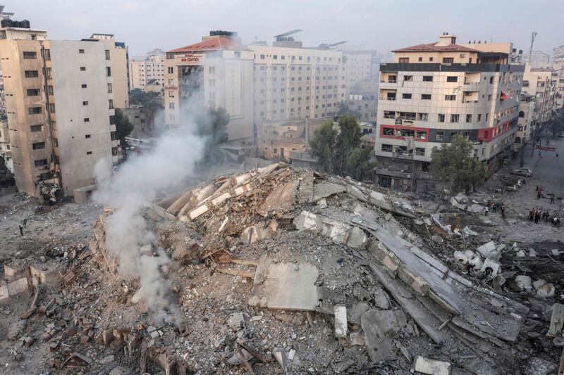 People walk around the ruins of a building destroyed in Israeli airstrikes in Gaza City. AFP