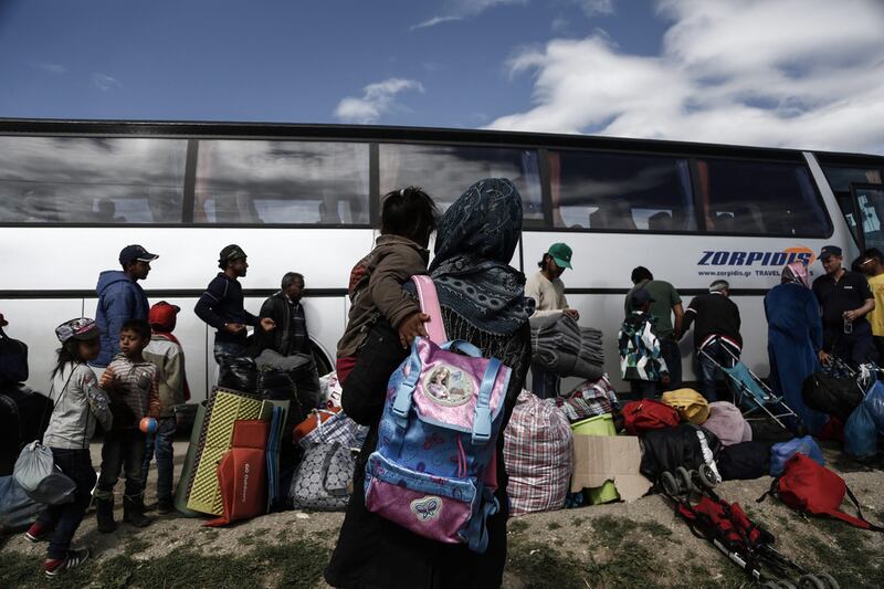 Syrian refugees stand outside a bus as they wait to be transferred to a hospitality centre during a police operation at a refugee camp on the border between Greece and the Former Yugoslav Republic of Macedonia (FYROM) on May 25, 2016. Yannis Kolesidis/EPA