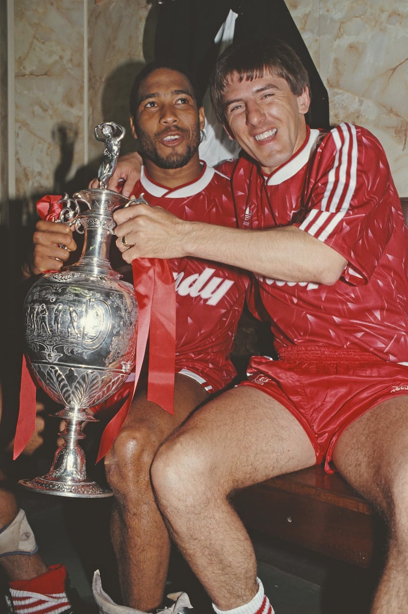 LIVERPOOL, UNITED KINGDOM - MAY 01: Liverpool players John Barnes (l) and Peter Beardsley celebrate in the dressing room with the First Divison Trophy after winning the 1989/90 First Division Championship after a 1-0 victory against Derby County on May 1, 1990 in Liverpool, England. (Photo by Dan Smith/Allsport/Getty Images)