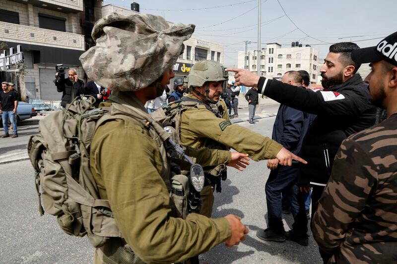 An Israeli soldiers speak to a Palestinianians near in the West Bank town of Hawara. Reuters