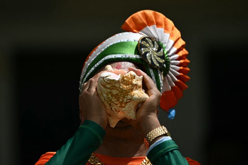 An India fan blows on a conch. AFP