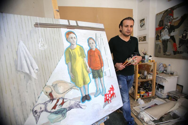 Iraqi refugee artist Saddam Al- Jumaily stands next to his paint with his sister at his home workshop in Amman, Jordan. (Salah Malkawi for The National)