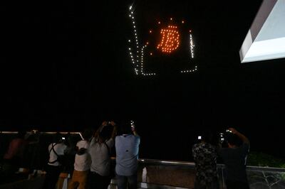 People take pictures as illuminated drones form figures inspired by the Bitcoin logo at a reception hosted by billionaire Brock Pierce on the first day of Bitcoin's implementation as a currency in El Salvador on September 7. AFP