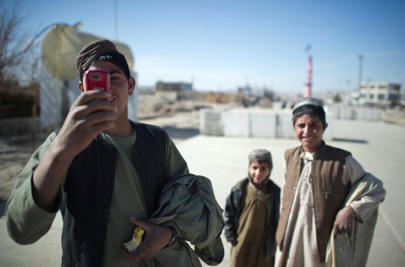 An Afghan youth uses his mobile phone to take pictures of US Marines from 1st Battalion, 8th Marines as they patrol around the town of Musa Qala on January 18, 2011. The top US military officer said January 12 he sees an increase in bloodshed in Afghanistan as allied forces step up their offensive against the Taliban. AFP PHOTO / DMITRY KOSTYUKOV / AFP PHOTO / DMITRY KOSTYUKOV