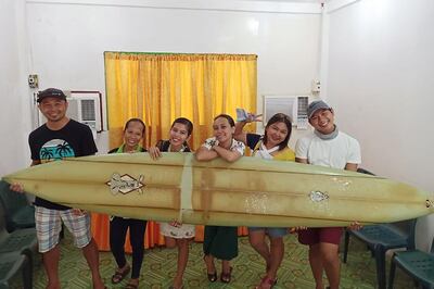 This undated handout photo received on September 18, 2020 courtesy of Giovanne Branzuela shows Filipino teacher Giovanne Branzuela (L) posing with his surfboard, once owned by big wave surfer Doug Falter who lost it while surfing in Hawaii, along with his villagemates on Sarangani island in the Philippines. When big wave surfer Doug Falter lost his board in a wipeout in Hawaii, his best hope was for a fisherman to find it. He never imagined it would be over 8,000 kilometres (5,000 miles) away in the southern Philippines. 
 - TO GO WITH PHILIPPPINES-SURFING,FOCUS BY MIKHAIL FLORES ---- RESTRICTED TO EDITORIAL USE - MANDATORY CREDIT "AFP PHOTO / COURTESY OF GIOVANNE BRANZUELA" - NO MARKETING NO ADVERTISING CAMPAIGNS - DISTRIBUTED AS A SERVICE TO CLIENTS --- NO ARCHIVE ---

 / AFP / Courtesy of Giovanne Branzuela  / Handout / TO GO WITH PHILIPPPINES-SURFING,FOCUS BY MIKHAIL FLORES ---- RESTRICTED TO EDITORIAL USE - MANDATORY CREDIT "AFP PHOTO / COURTESY OF GIOVANNE BRANZUELA" - NO MARKETING NO ADVERTISING CAMPAIGNS - DISTRIBUTED AS A SERVICE TO CLIENTS --- NO ARCHIVE ---


