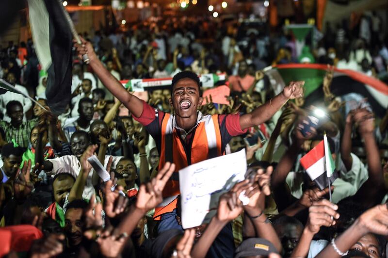 TOPSHOT - Sudanese protesters wave flags and flash victory signs as they gather for a sit-in outside the military headquarters in Khartoum on May 19, 2019. Talks between Sudan's ruling military council and protesters are set to resume, army rulers announced, as Islamic movements rallied for the inclusion of sharia in the country's roadmap. / AFP / Mohamed el-Shahed
