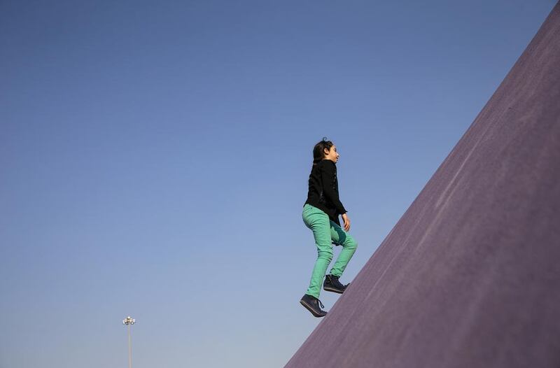 A girl runs up a small incline wall as she and her family play at a new multipurpose park in Abu Dhabi. Silvia Razgova / The National