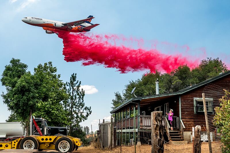 Karyn Larson watches a plane drop retardant as the Electra Fire burns towards her home in the Pine Acres community of Amador County, California. AP Photo