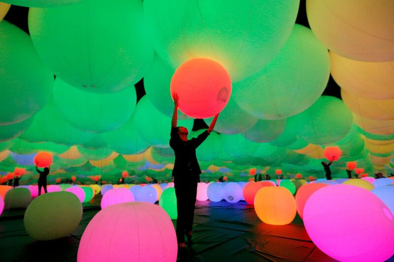 A visitor plays with glowing balloons during a digital art exhibition at a shopping mall in Jakarta, Indonesia.  AP