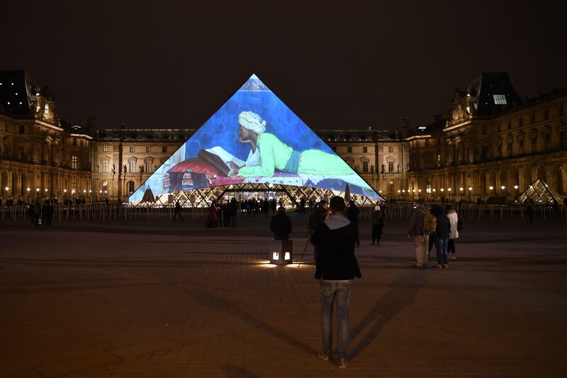 Images of the art displayed in the Louvre Abu Dhabi are projected onto the Louvre Pyramid in Paris Wednesday night to mark the opening of the museum on Saadiyat island. Eric Feferberg / AFP