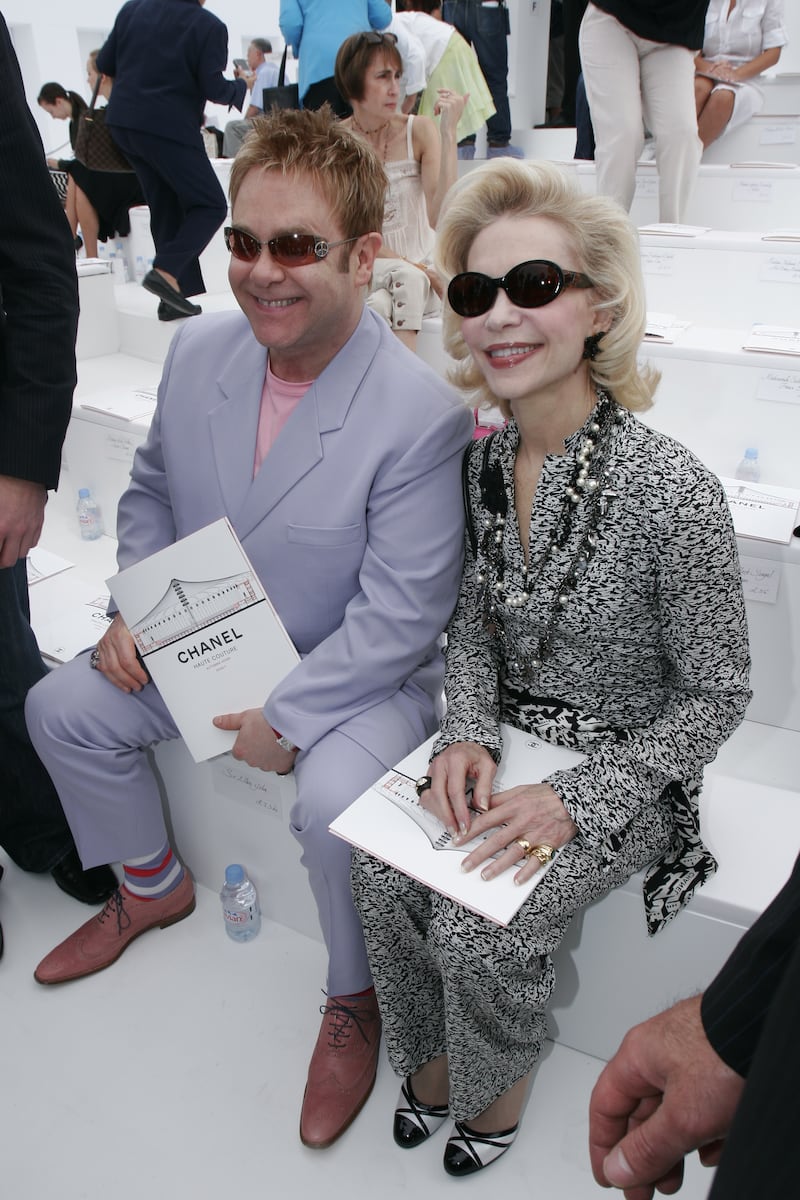 Elton John, in a lilac suit and pink T-shirt, and Lyne Wyatt attend the Chanel haute couture autumn/winter 2006/07 show during Paris Fashion Week on July 6, 2006. Getty Images
