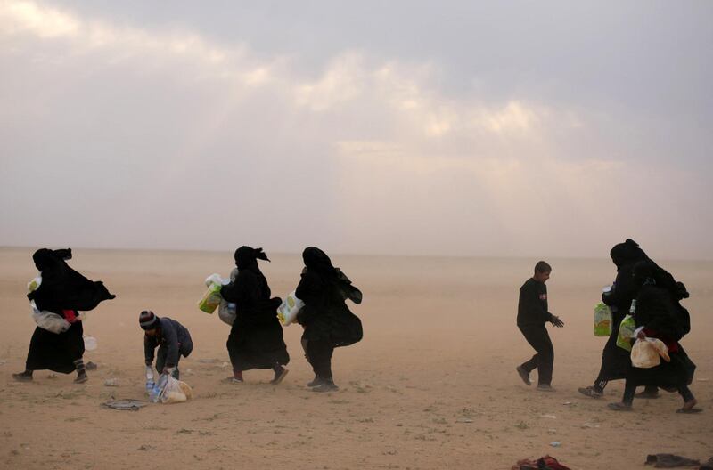 Women walk with their belongings near the village of Baghouz, Syria. Reuters