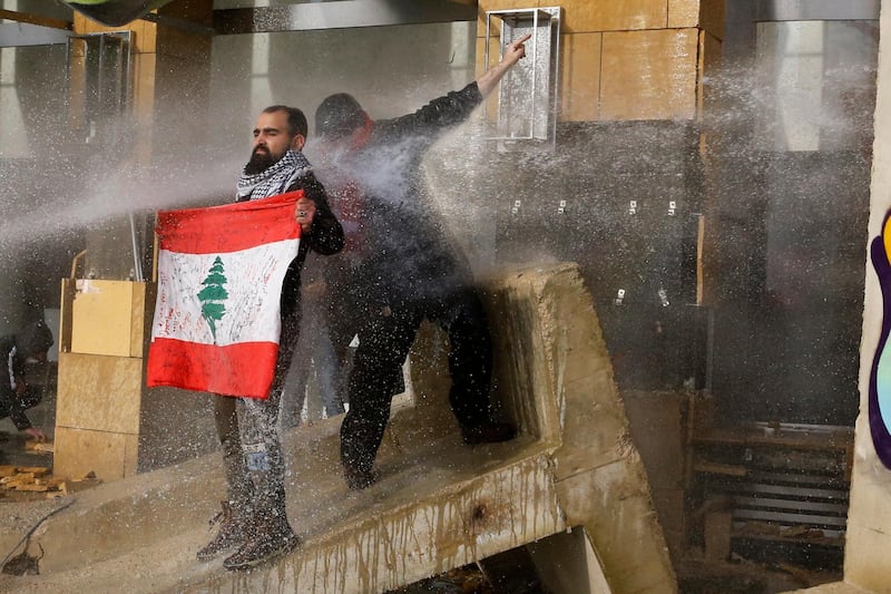 Riot police spray anti-government protesters with water cannons during a protest against a parliament session preparing a vote of confidence for the new government in Beirut, Lebanon. AP Photo