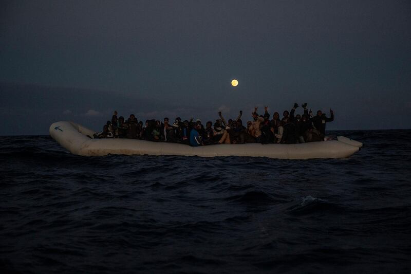 Migrants and refugees from different African nationalities react on an overcrowded rubber boat, as aid workers of the Spanish NGO Open Arms approach them in the Mediterranean Sea, international waters, off the Libyan coast.  AP