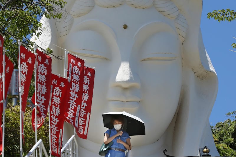 A woman wearing a face mask to protect against the spread of the coronavirus walks down stone steps at the Ofuna Kannon Buddhist temple in Kamakura, near Tokyo. AP Photo