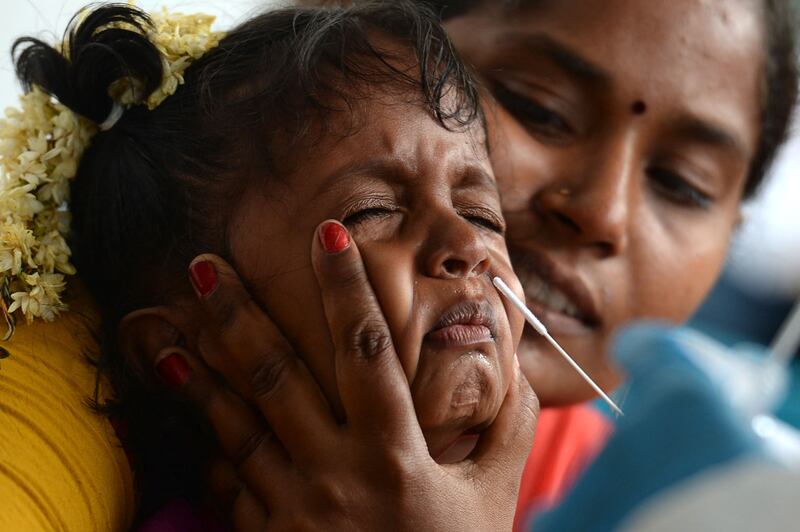 A health worker collects a swab sample from a child arriving on an international flight at Chennai International Airport.