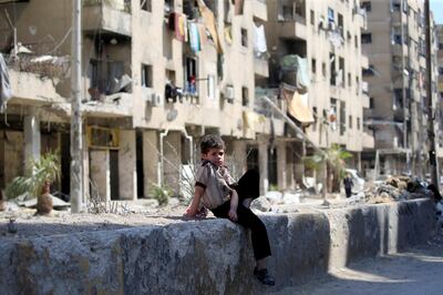 A child sits in a street during a media tour in Douma near Damascus, Syria April 23, 2018. REUTERS/ Ali Hashisho