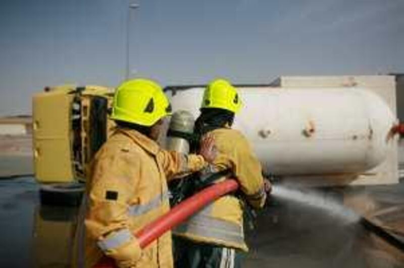 Dubai - February 18, 2009: Mohammad Al Balushi (right) and Ibrahim Yousef Al Hossani spray water on a truck during training of a simulated gas leak from a liquified petroleum gas truck rollover at the Civil Defence Training Centre in Al Aweer. ( Philip Cheung / The National ) *** Local Caption ***  PC0185-EmergencyResponse.jpg
