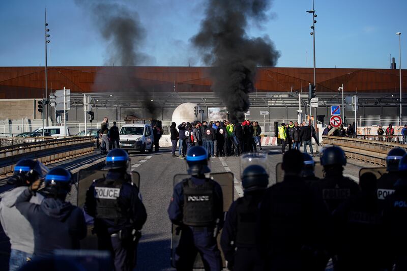 Dockers face riot police as a barricade burns near the port of Marseille. AP