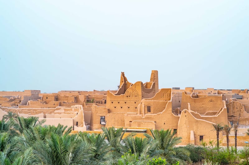 Silhouette of Salwa Palace in At-Turaif in Ad Diriyah with palm trees in foreground. Photo by THAMER AL AHMADI