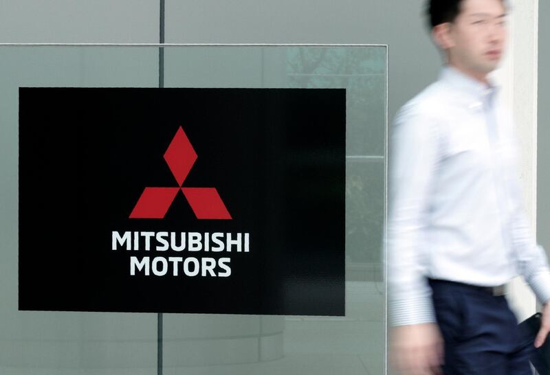 FILE - In this June 21, 2019, file photo, a man walks past a sign of Mitsubishi Motors at its headquarter in Tokyo Friday, June 21, 2019. Mitsubishi Motors Corp. reported Monday, July 27, 2020, a 176 billion yen ($1.7 billion) loss for April-June, and forecast more red ink for the fiscal year, as the coronavirus pandemic slammed auto demand around the world. (AP Photo/Eugene Hoshiko, File)