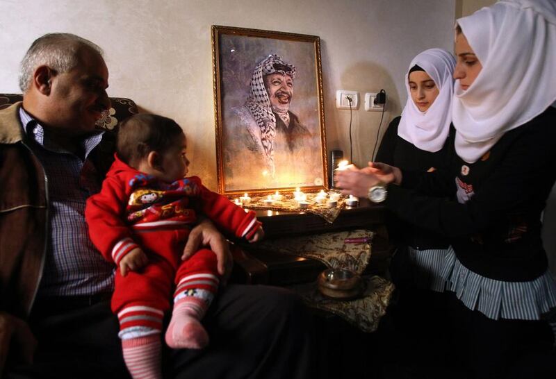 A Palestinian family lights candles in front of a portrait of late Palestinian leader Yasser Arafat on November 2, 2014, at a house in the West Bank town of Hebron.  Hazem Bader/AFP Photo