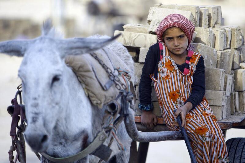 An Iraqi girl rides a cart carrying bricks as she works at a brick factory near the central Iraqi shrine city of Najaf. Five out of seven brick factories in the region have been hit by flood water following heavy rainfall. Haider Hamdani / AFP