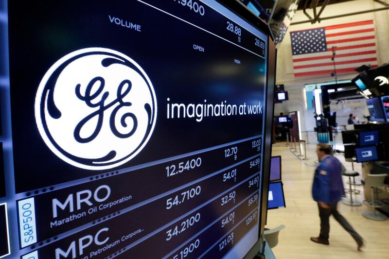 FILE - In this Monday, June 12, 2017, file photograph the General Electric logo appears above a trading post on the floor of the New York Stock Exchange. EU authorities are accusing General Electric, drugmaker Merck and electronics manufacturer Canon of violating European rules to push through mergers or acquisitions. The Commission is not seeking to annul the mergers, but threatening hefty fines if further investigation confirms wrongdoing. (AP Photo/Richard Drew, File)