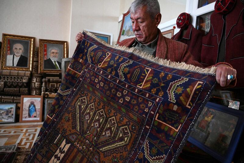 A man displays a carpet at his shop in Bamiyan, Afghanistan. Rug hunters can spend months visiting villages to amass a diverse selection of pieces. AFP