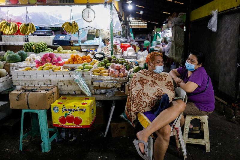 Vendors wearing face masks for protection against Covid-19 chat beside a fruit stand at a market in Quezon City, Metro Manila, Philippines. Reuters