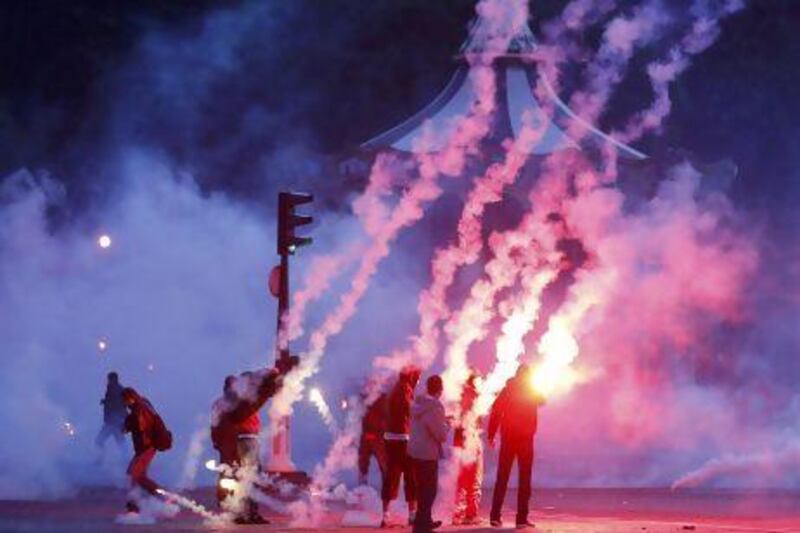 Smoke from tear gas and fireworks fill the air during clashes between police and supporters of Paris Saint-Germain.