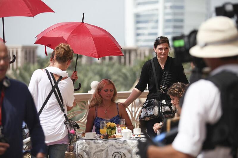 Jessica Boehrs, seated in the centre, is cooled off by an aide with an umbrella between takes.