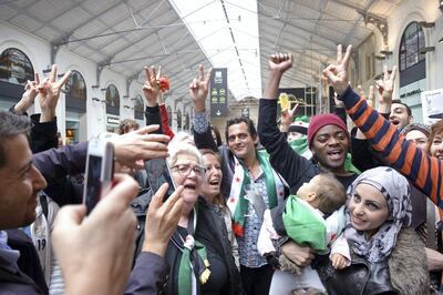 Syrian-American pianist and composer Malek Jandali (C) flahses the sign for victory after performing on a public piano in the middle of a crowd in a railway station mall in Paris on May 8, 2014. Jandali played to carry the voice of Syrian children to the Parisian public, just hours after the centre of his home-city, Homs, was evacuated by fighters opposed to Syrian president Bashar Al-Assad. AFP PHOTO / AMMAR ABD RABBO (Photo by AMMAR ABD RABBO / AFP)