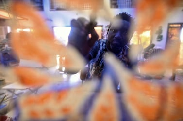Senegalese artist Omar Ba paints orange leaves on a pane of glass in his studio in Bambilor, Senegal. Cooper Inveen / Reuters