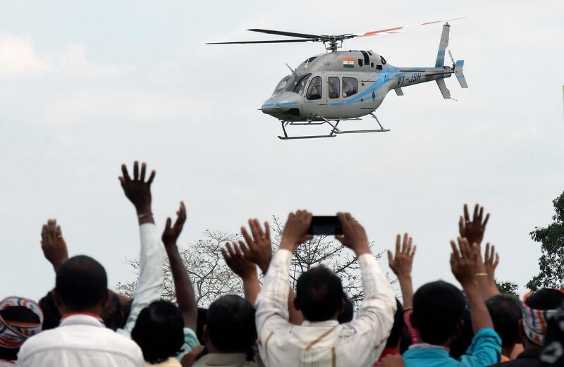 Supporters wave to Congress President Rahul Gandhi's helicopter as he arrives to address an election rally in Bokakhat, Golaghat district of Assam. EPA